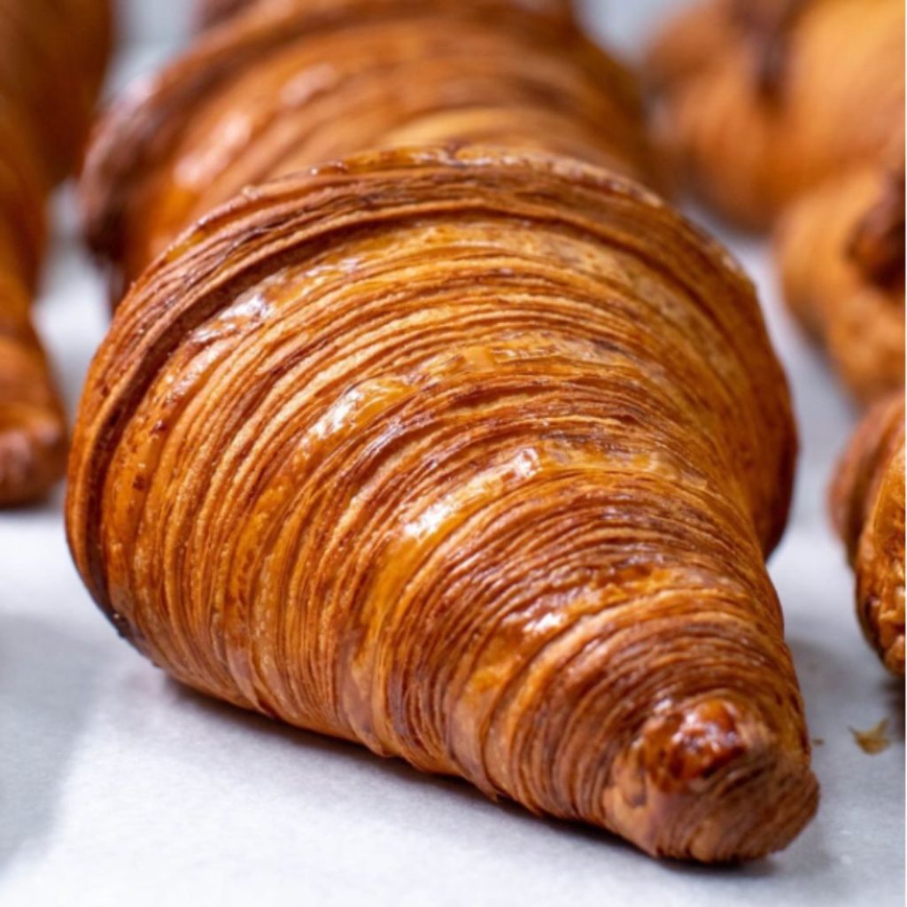 Close-up of a perfectly layered butter croissant at LDC Kitchen + Coffee, popular neighbourhood bakery in Dubai.