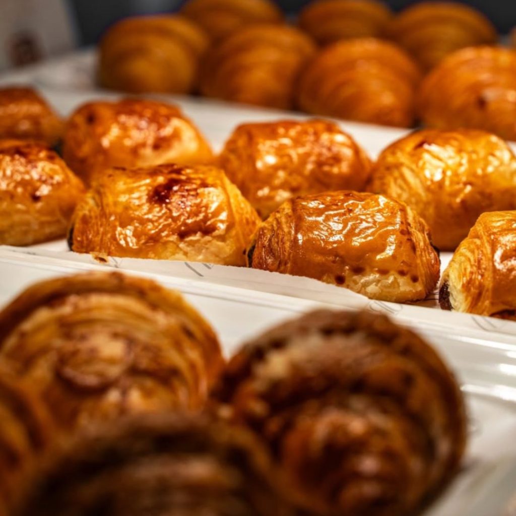 Tray of spiral croissants under warm lights at Risen Café & Artisanal Bakery on Marina Walk, Dubai.
